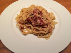Piatto di carbonara con guanciale, spaghetti e tuorlo d'uovo, evidenziando un errore comune nella preparazione.