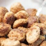 Polpette morbide appena sfornate su un piatto, guarnite con prezzemolo fresco.