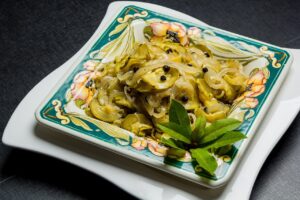 Zucchine alla scapece napoletane pronte, condite con aceto, aglio e menta, su un piatto decorativo.