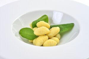 Gnocchi morbidi appena cotti su un piatto, con una spolverata di parmigiano grattugiato.